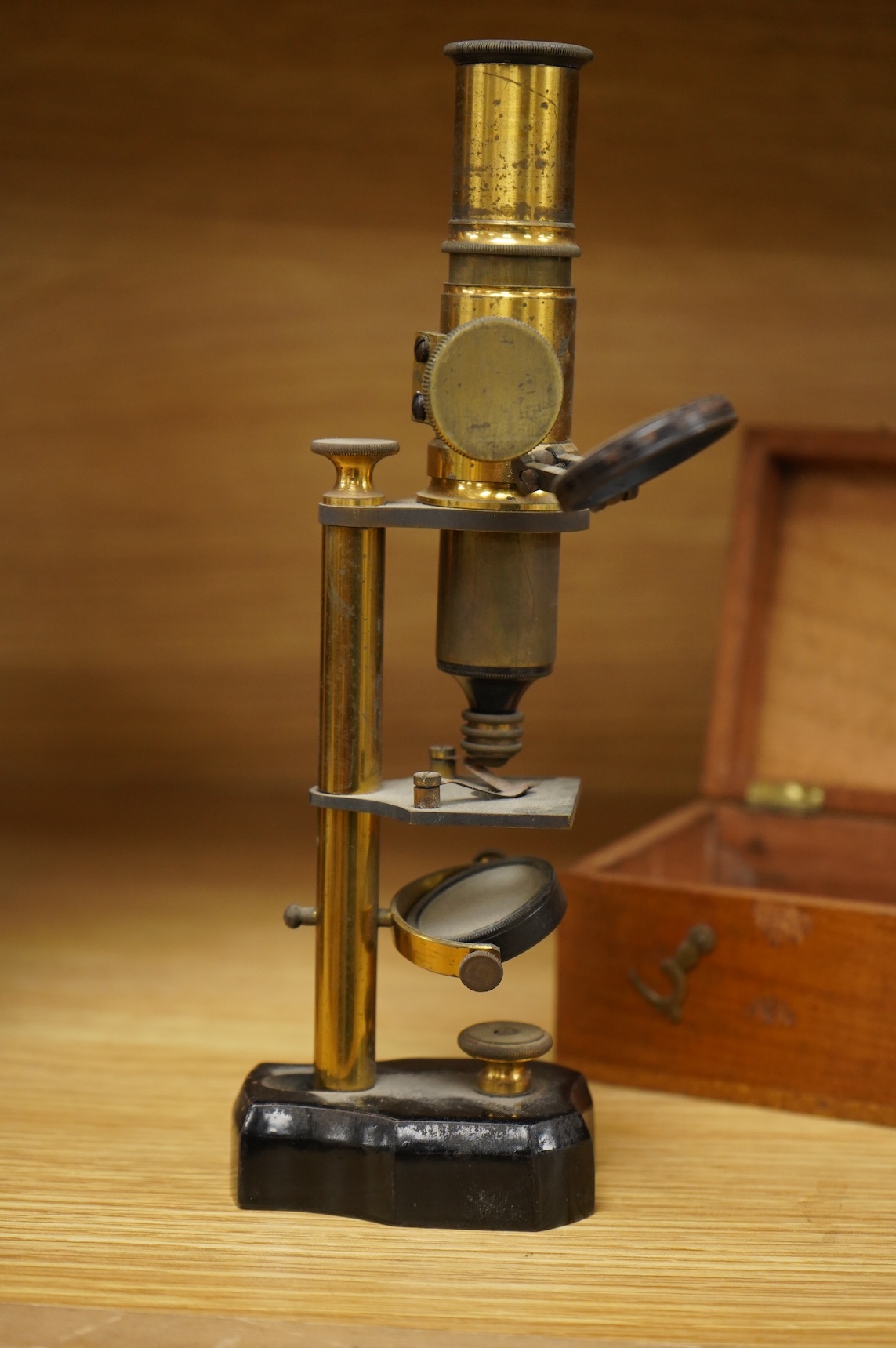 A late 19th/early 20th century French brass compound monocular microscope, height 20.5cms, together with a teak case; 23cm wide, 9cm deep, 7cm high